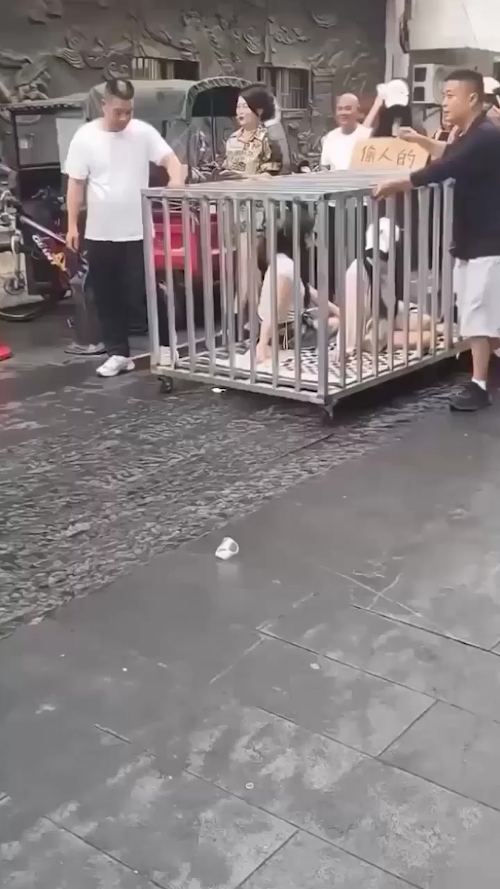 湖南汨罗商业街 惊现活人浸猪笼 俩女一狗被关铁笼 敲锣游街太疯狂！
